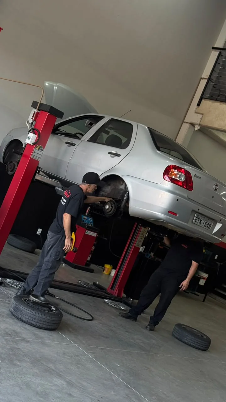 Equipe realizando manutenção em veículo elevado